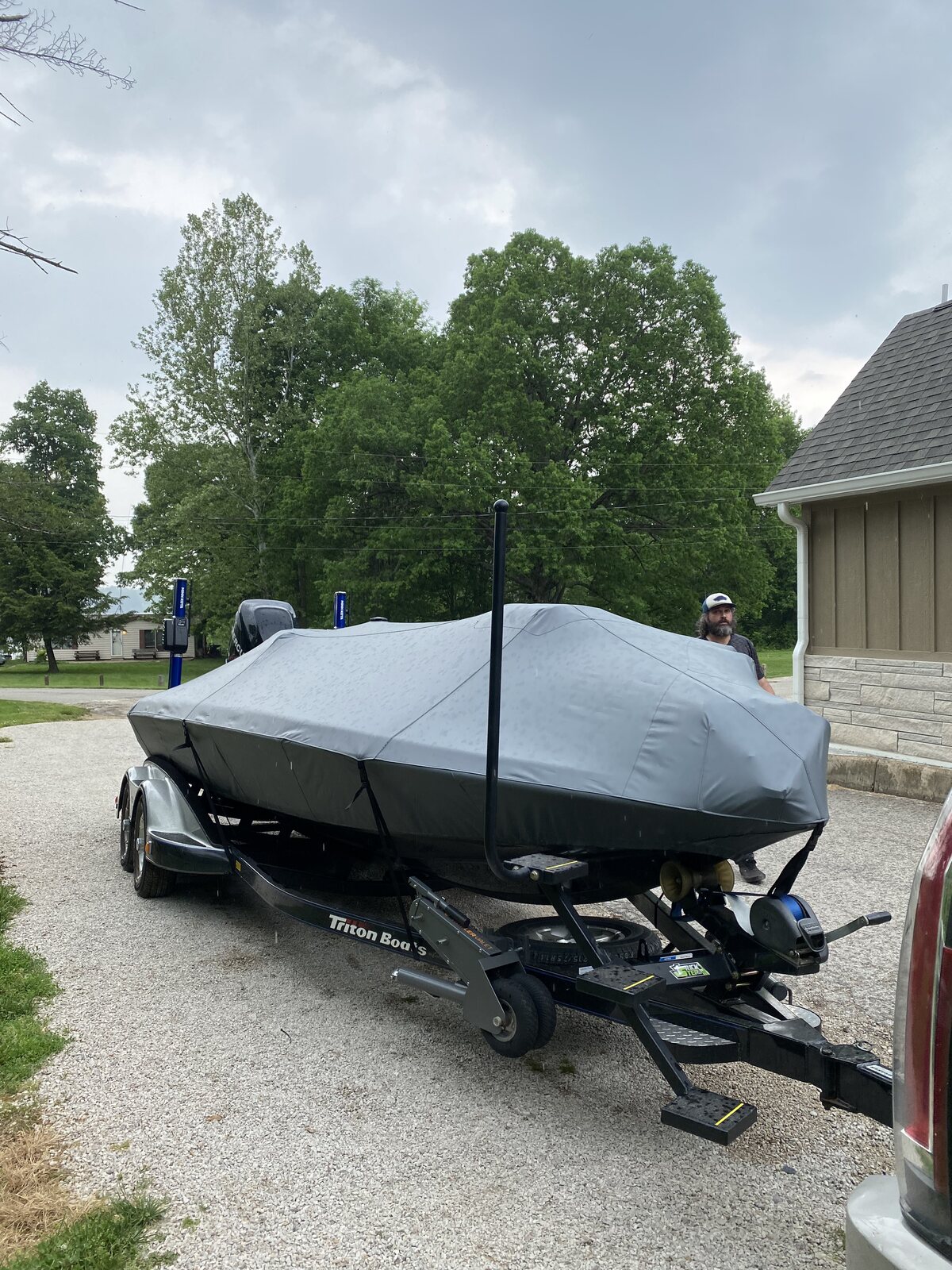 Charcoal fitted boat cover on a trailer in a driveway